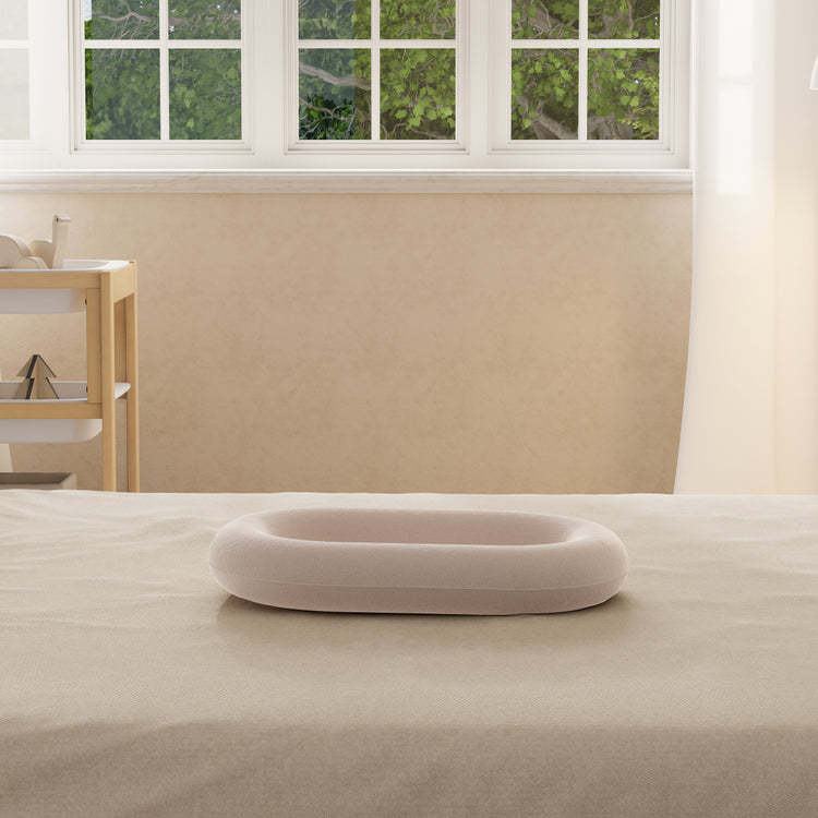 Inflatable ring on a bed in a room with a window and beige walls.