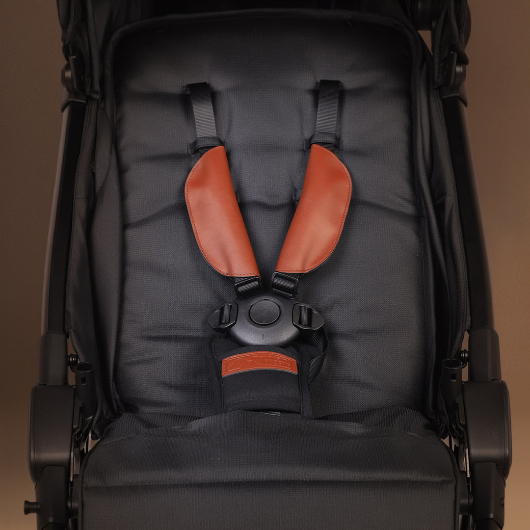 Closeup of the Mountain Buggy nano urban in black seat with the brown stray covers on display shown against a brown background