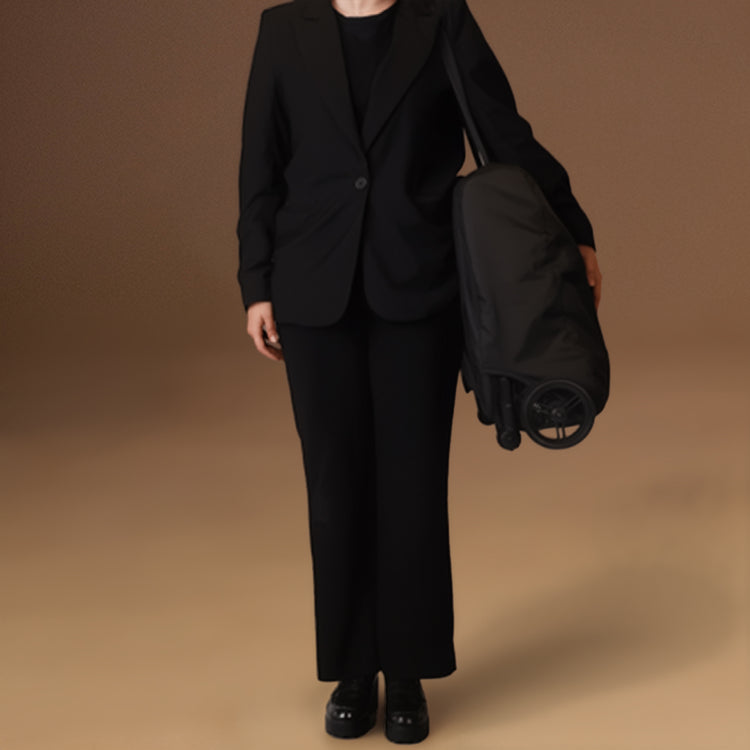 Person wearing a black suit holding the Mountain Buggy nano urban under one arm to showcase the lightweight buggy folded