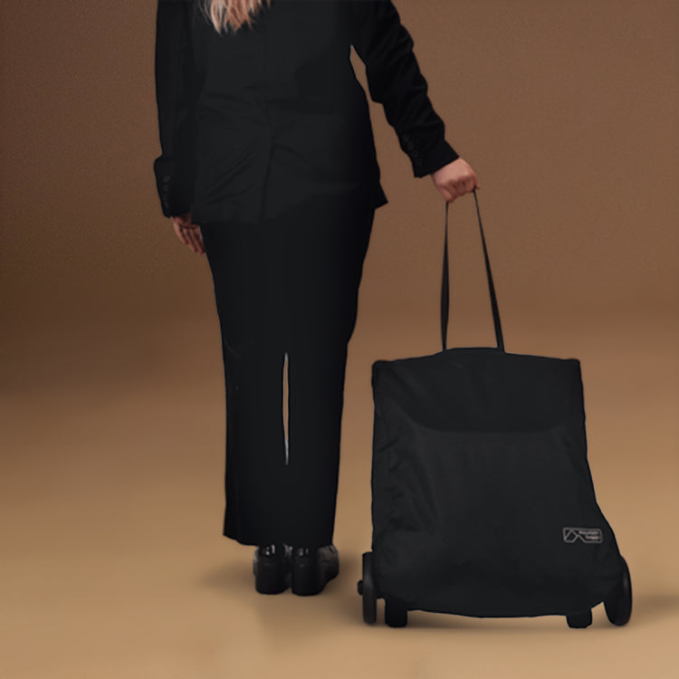 Person wearing a black suit pulling the Mountain Buggy nano urban with one arm to showcase the lightweight buggy folded and in travel bag