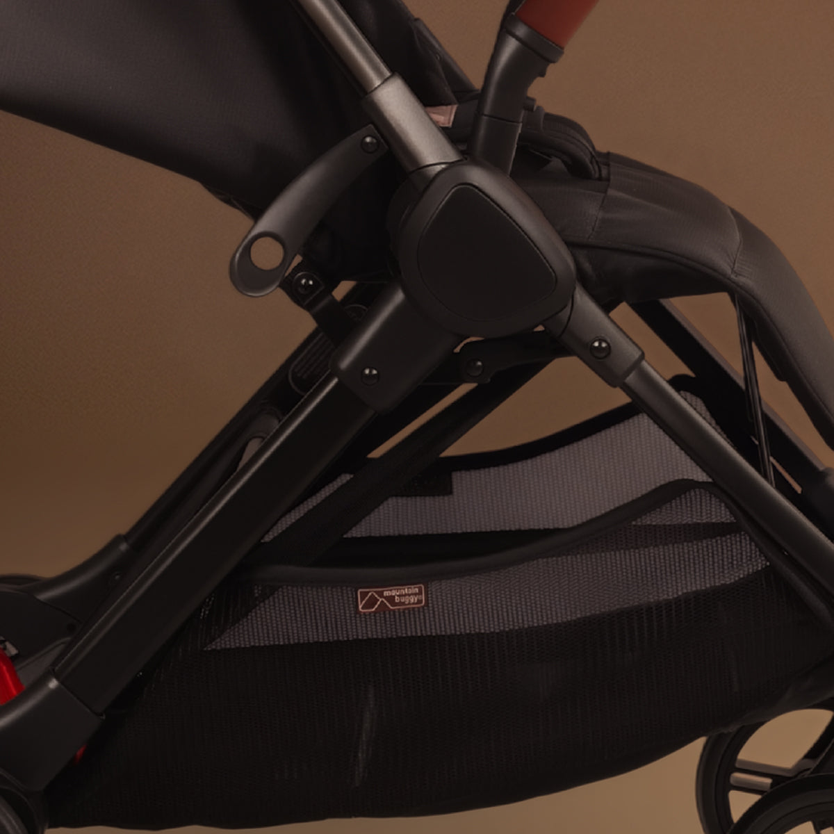 Close up of the Mountain Buggy nano urban in black shown against a brown background showing the storage tray and frame