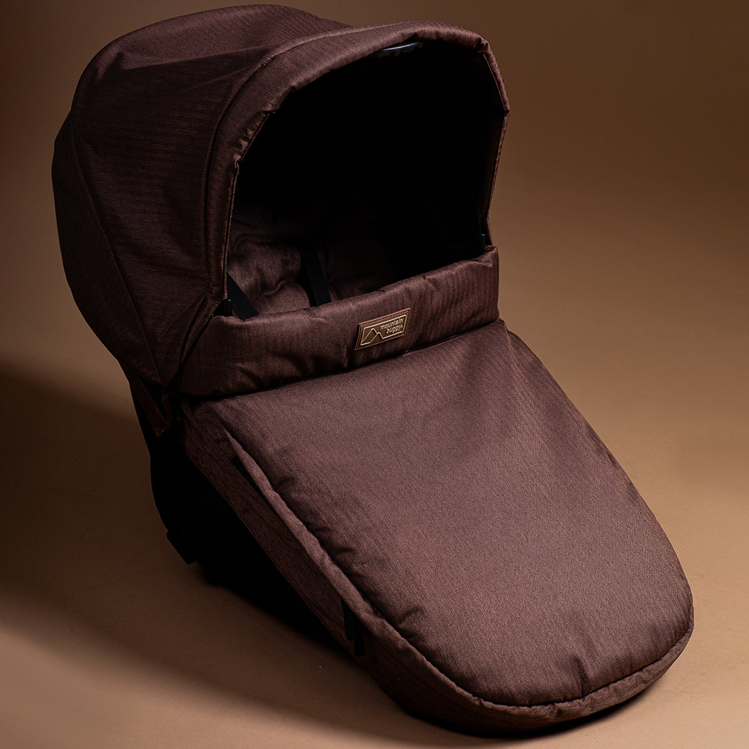 Full shot of Mountain Buggy carry cot plus in toddler mode with mustang brown colouring on brown background