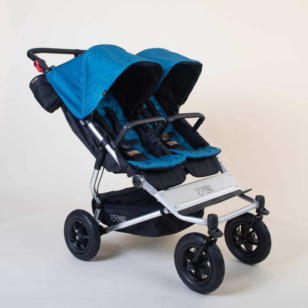 Full shot of Mountain Buggy duet in ocean blue double front facing setup on a white background
