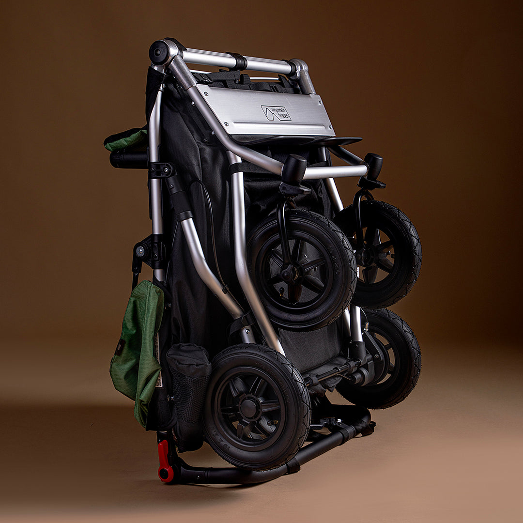 Full shot of Mountain Buggy duet in matcha green folded on brown background