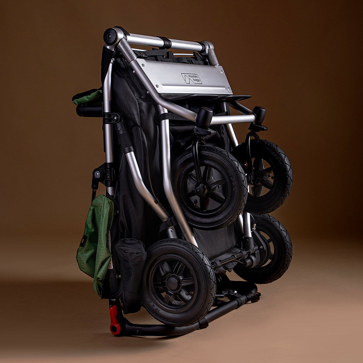 Full shot of Mountain Buggy duet in matcha green folded on brown background
