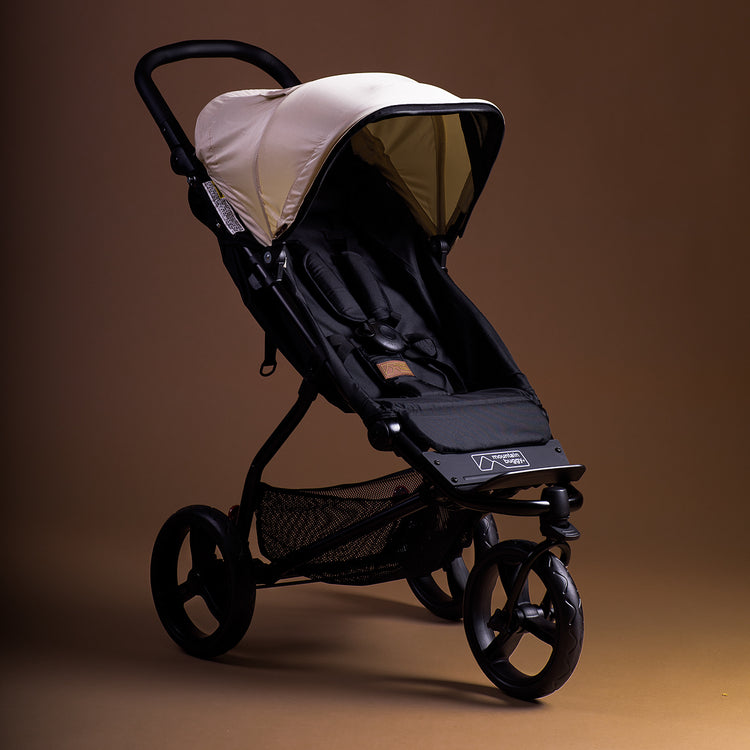 Full angled shot of the Mountain Buggy swift in ivory shown on a brown background