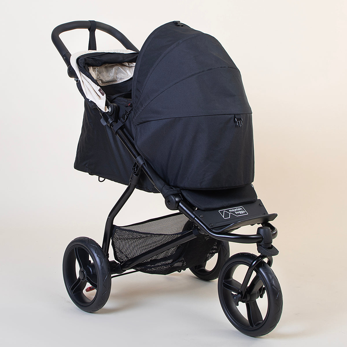Full angled shot of the Mountain Buggy swift in ivory with the optional cacoon and fully open sun shade shown on a white background