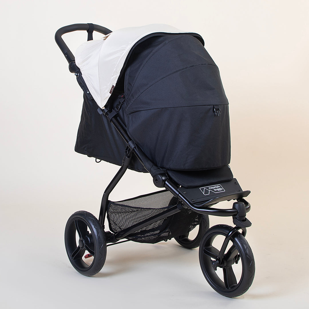 Full angled shot of the Mountain Buggy swift in ivory with the optional cacoon and fully closed sun shade shown on a white background