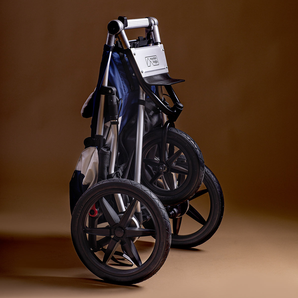 Full shot of the Mountain Buggy terrain in quartz folded up shown on a brown background