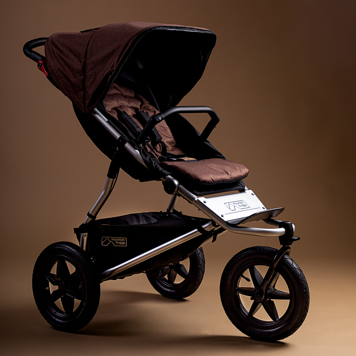 Full shot of the Mountain Buggy urban jungle in mustang brown shown on a brown background