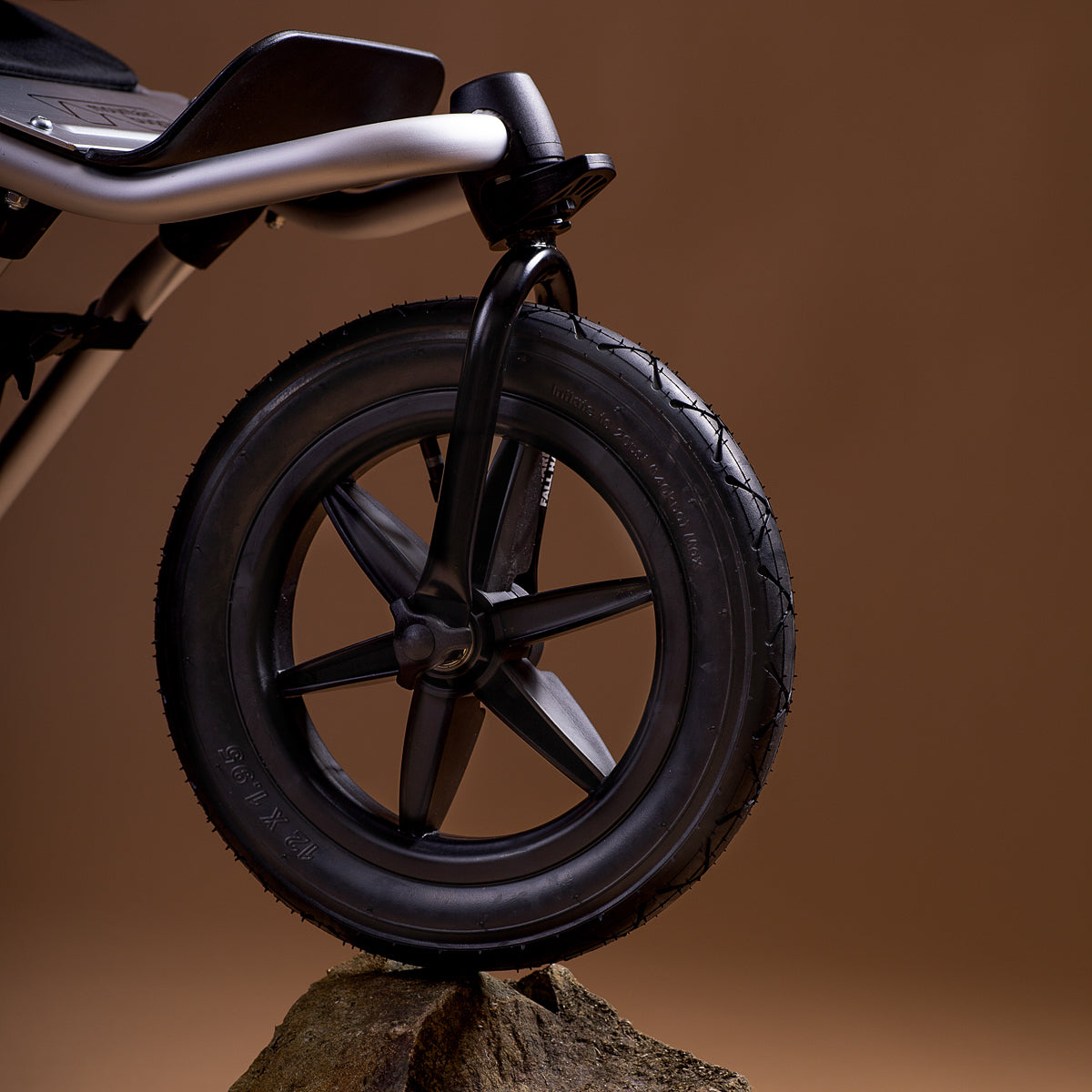 close up of the Mountain Buggy urban jungle front wheel on a rock shown on a brown background