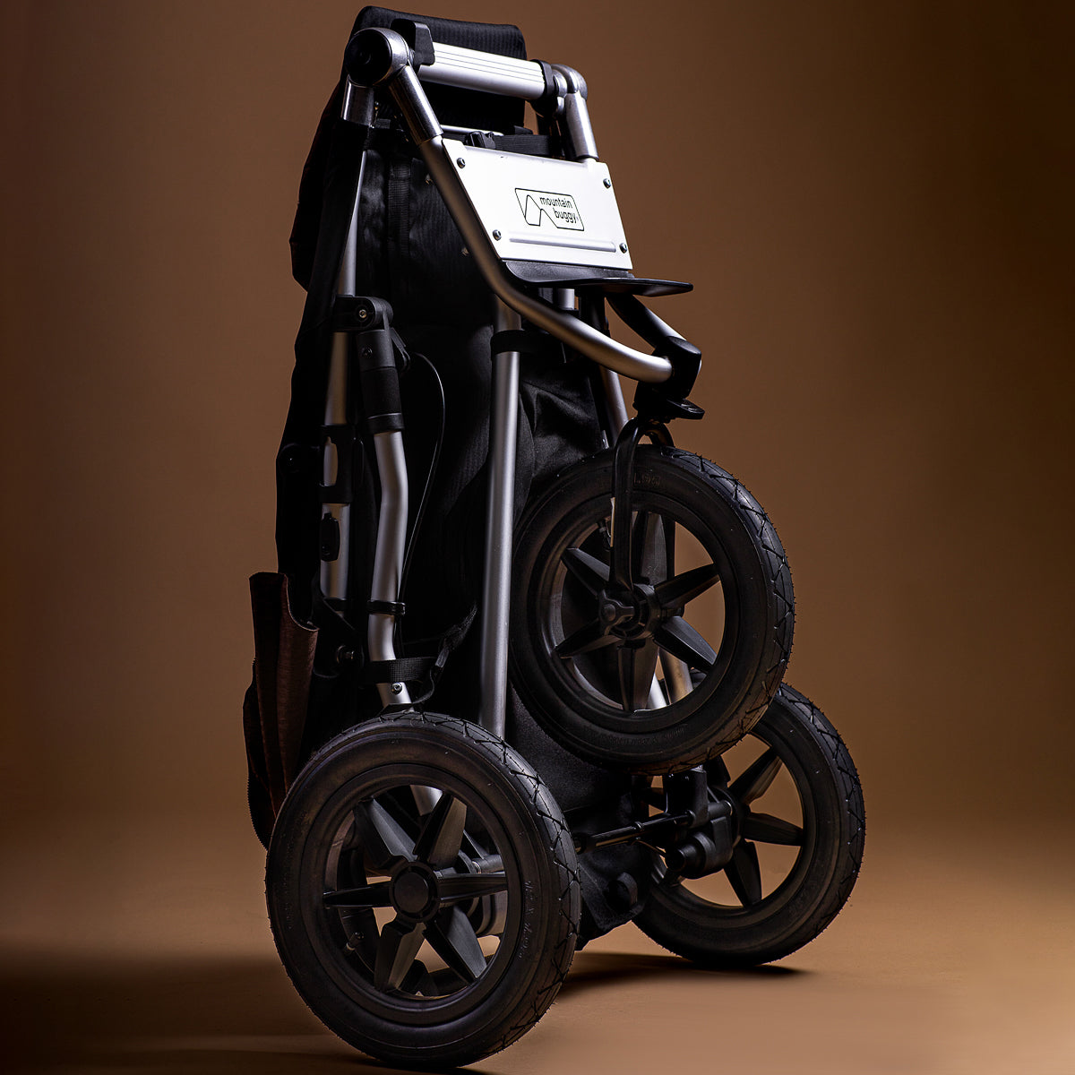 Full shot of the Mountain Buggy urban jungle folded up on a brown background