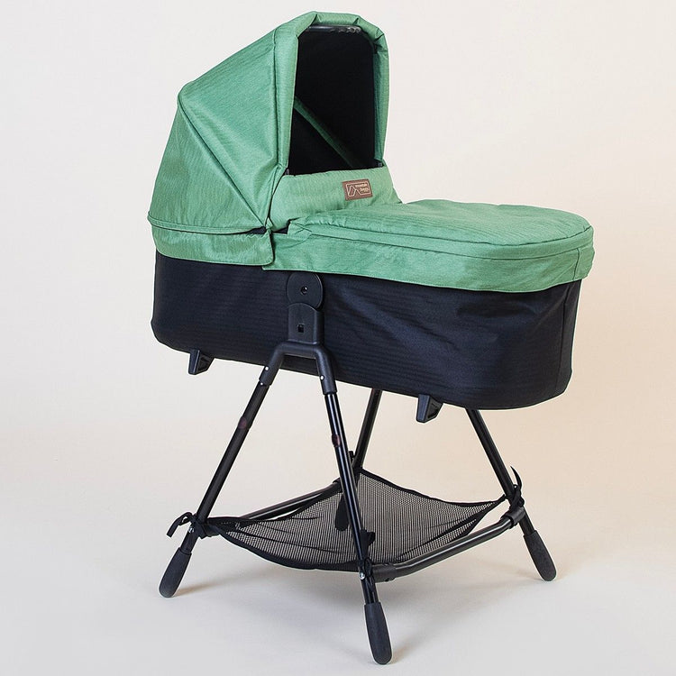 Full shot of Mountain Buggy carry cot plus for duet in matcha green with stand on white background
