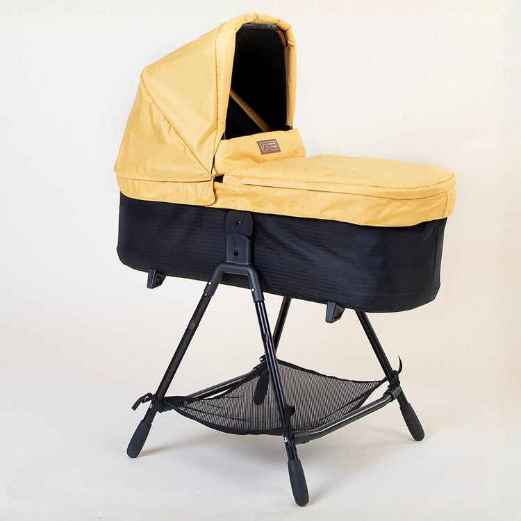 Full shot of Mountain Buggy carry cot plus for duet in solare yellow with stand on white background