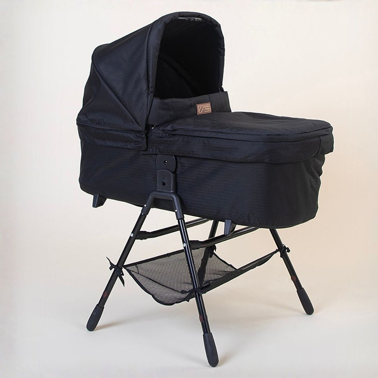 Full shot of the Mountain Buggy urban jungle carrycot plus in caviar black on the stand accessory on a white background 