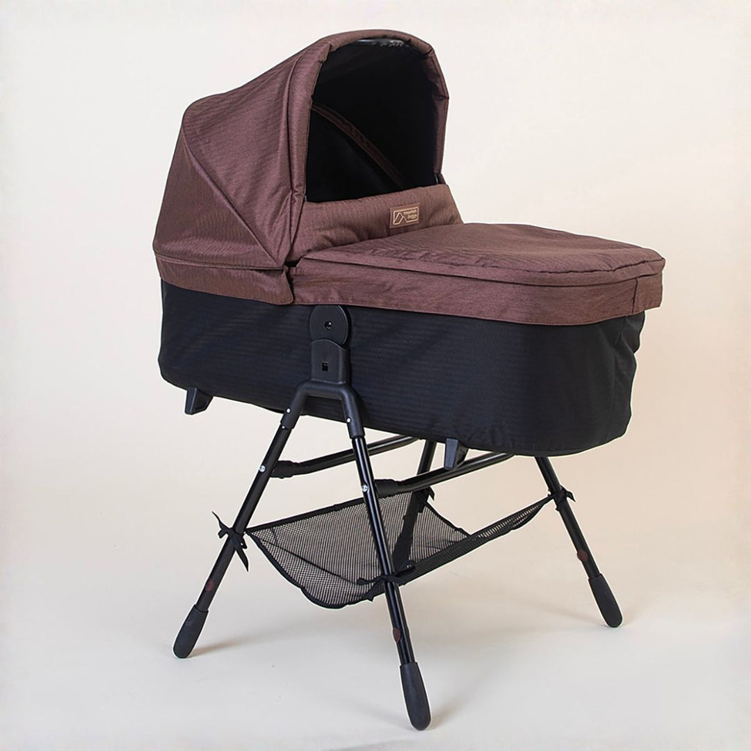 Full shot of the Mountain Buggy urban jungle carrycot plus in mustang brown on the stand accessory on a white background 
