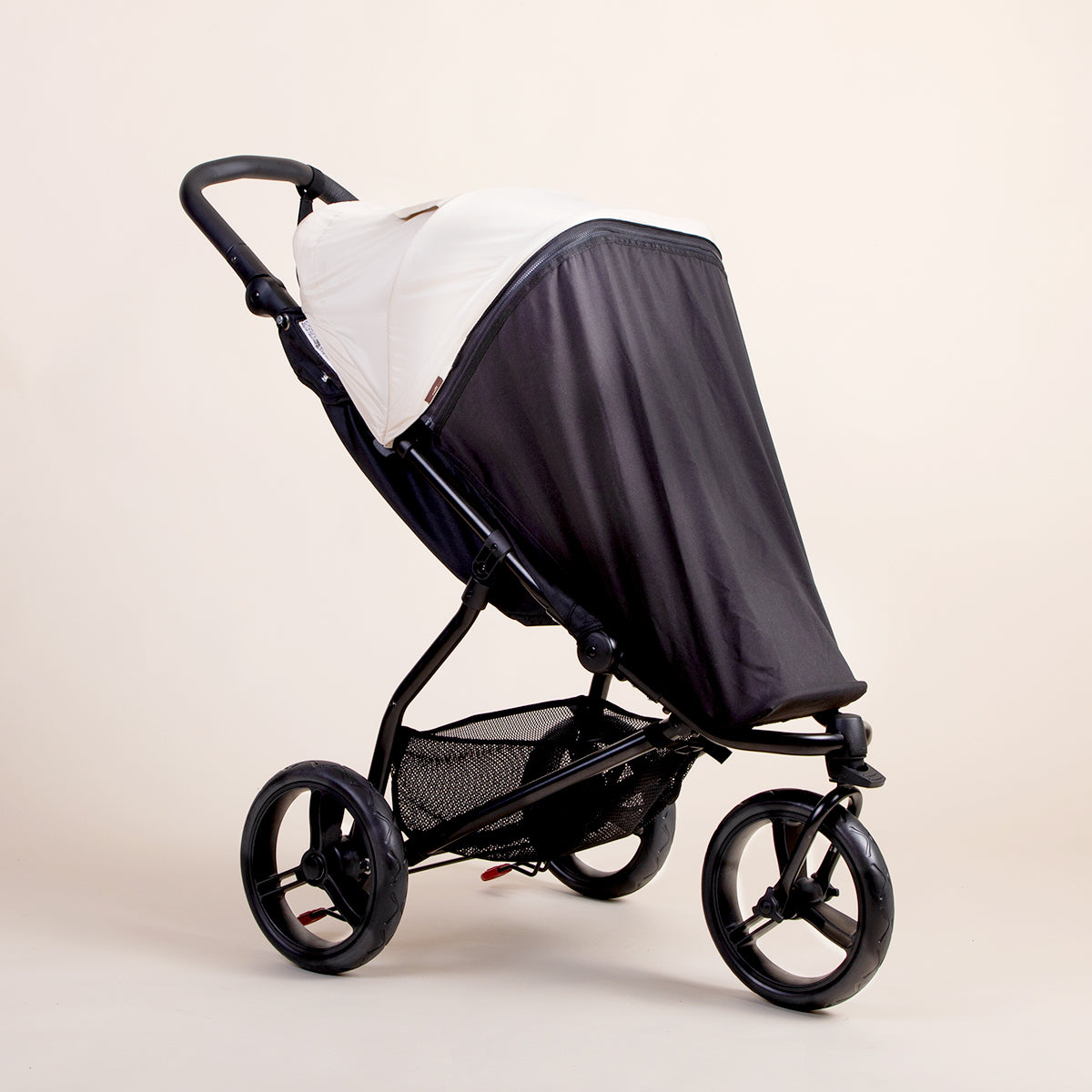 Full shot of the Mountain Buggy swift blackout cover ontop of a Mountain Buggy swift in ivory