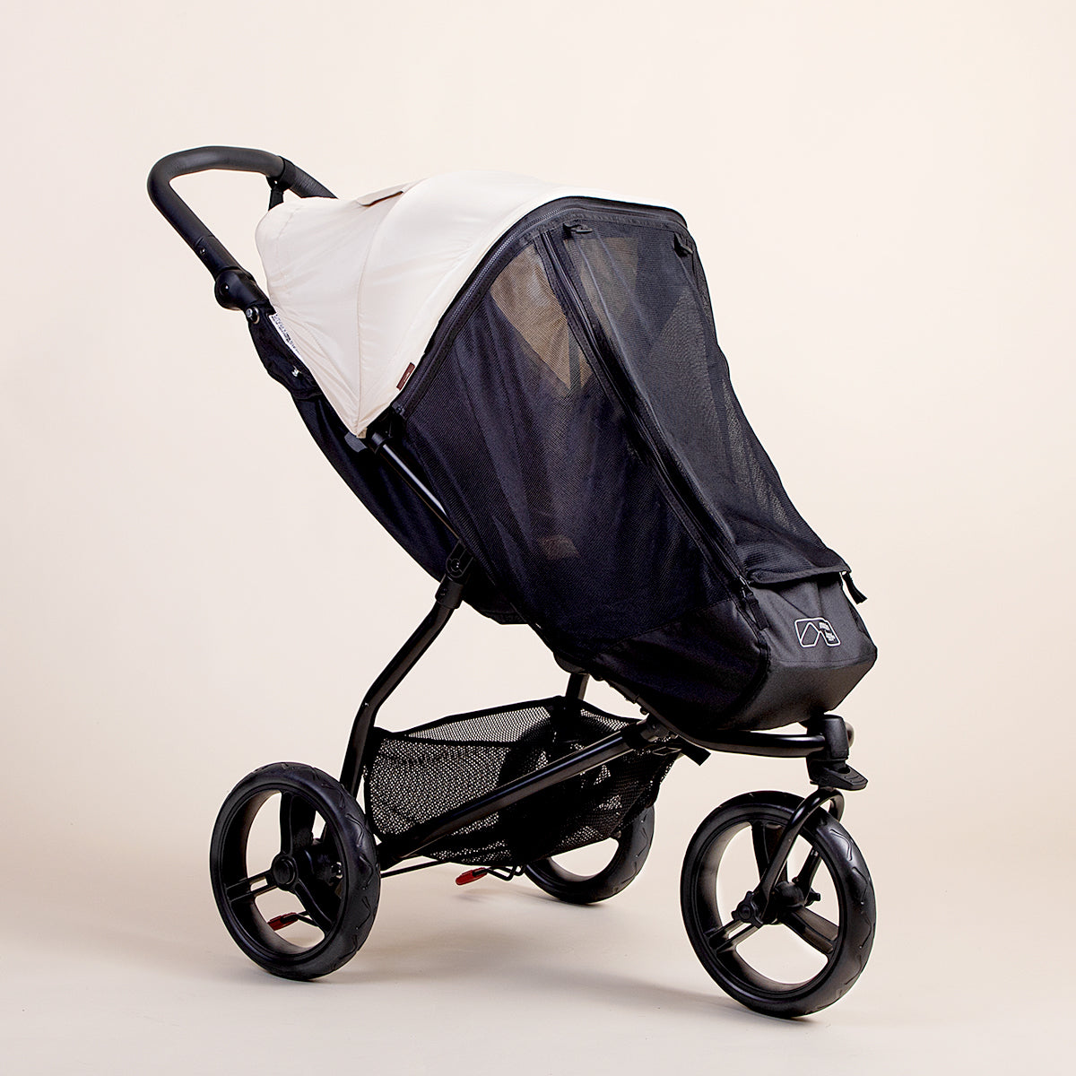 Full shot of the Mountain Buggy swift mesh cover ontop of a Mountain Buggy swift in ivory
