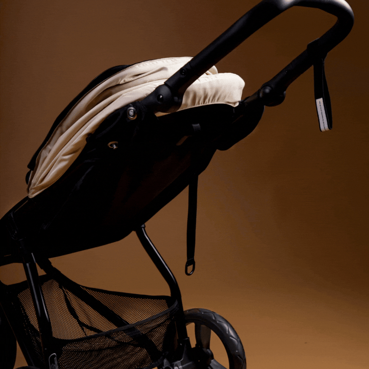 Full angled shot of the Mountain Buggy swift in ivory gif of the reclining seat shown on a brown background