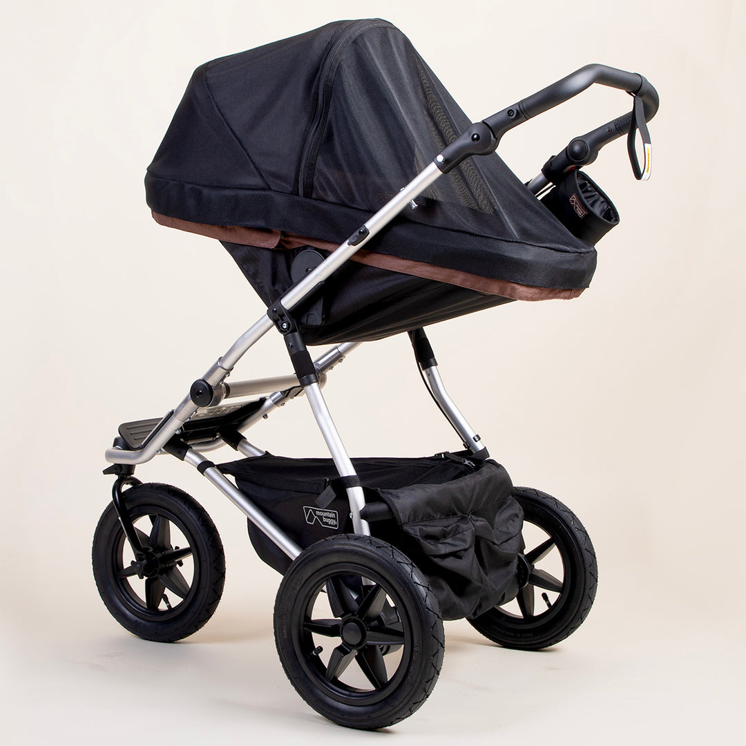 full shot of a mountain buggy urban jungle carrycot plus mesh cover on a mustang brown carrycot plus in toddler mode