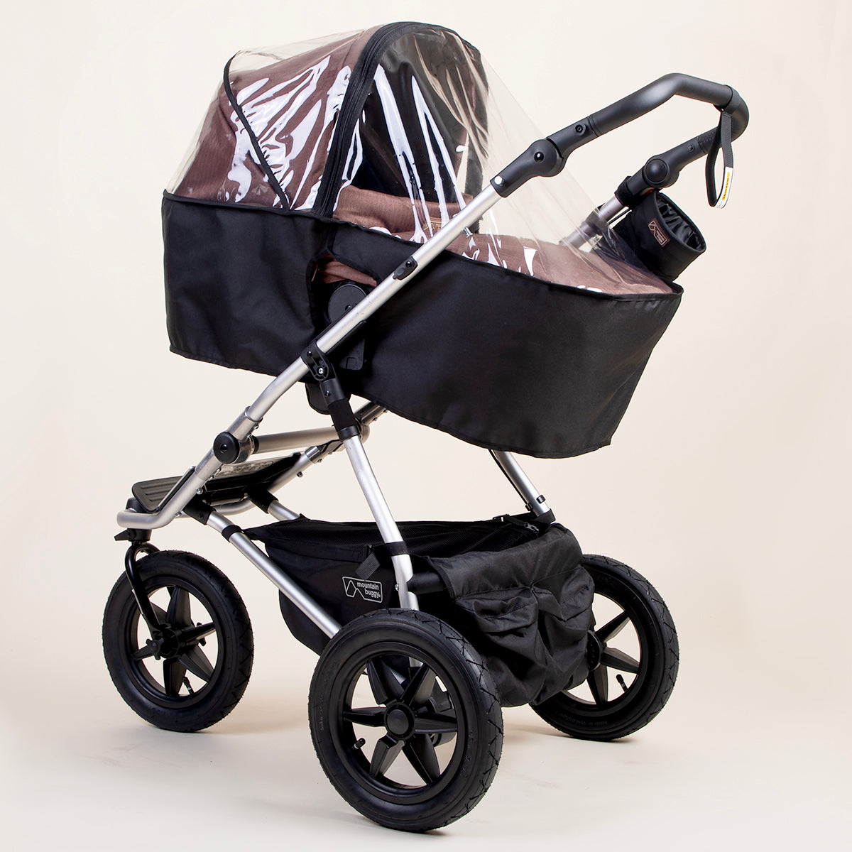 full shot of a mountain buggy urban jungle carrycot plus storm cover on a mustang brown carrycot plus in toddler mode