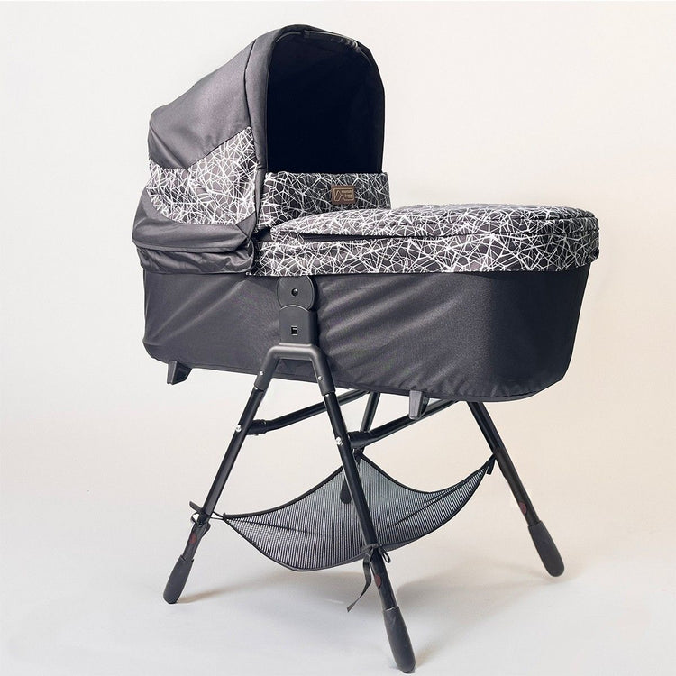Full shot of Mountain Buggy carry cot plus for terrain in graphite with stand on white background