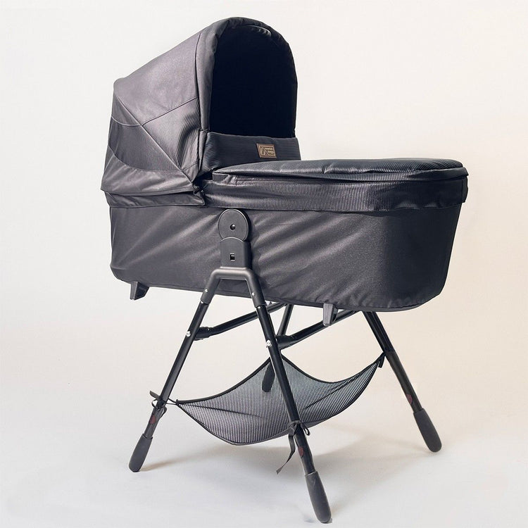 Full shot of Mountain Buggy carry cot plus for terrain in onyx with stand on white background