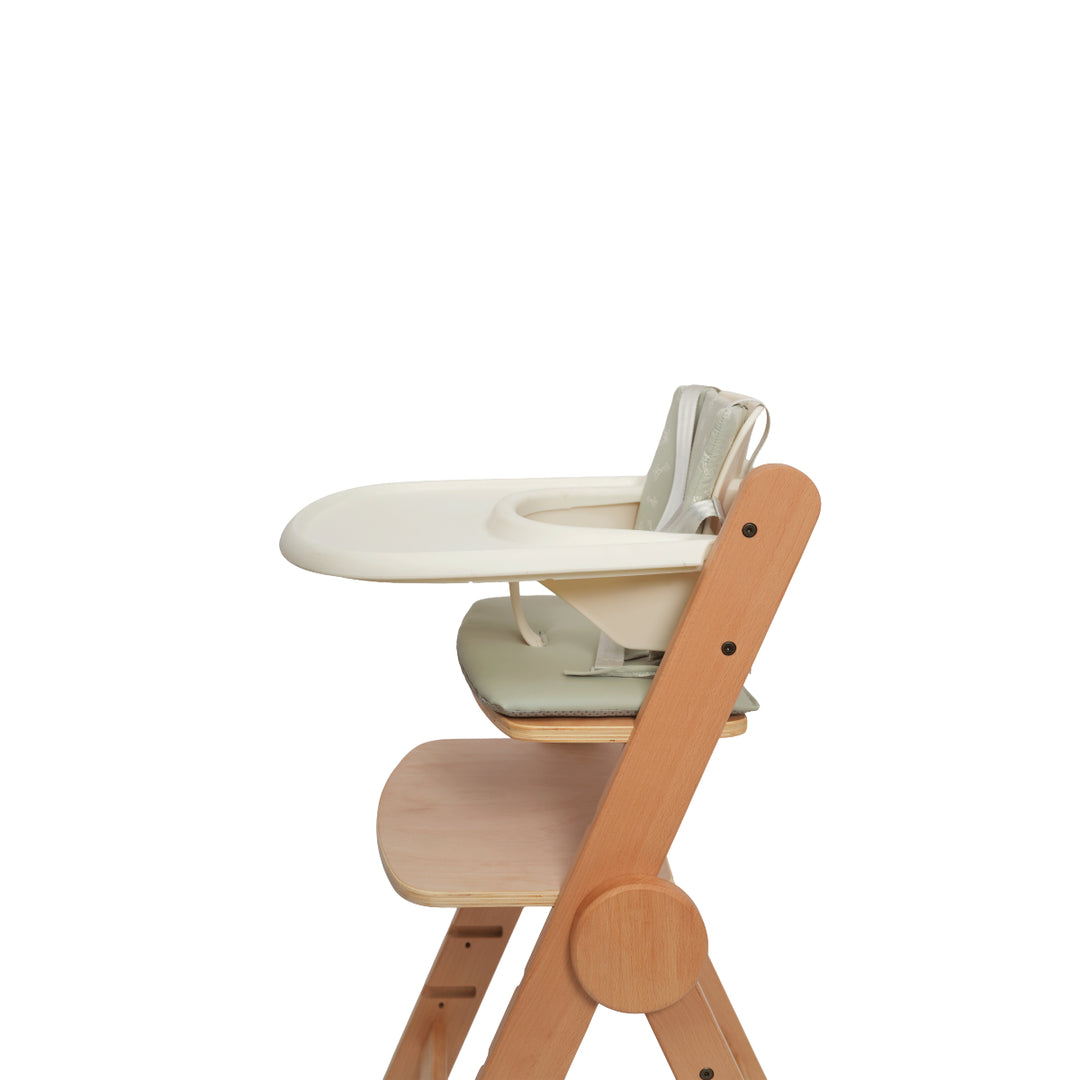 Close up side view of ORIGIN Camoline Wooden Highchair with baby setup and tray in natural wood finish.
