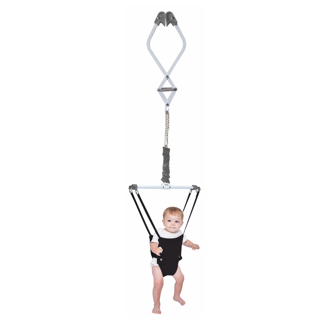 Baby in a black harness being lifted by a gray and white lifting device on a white background