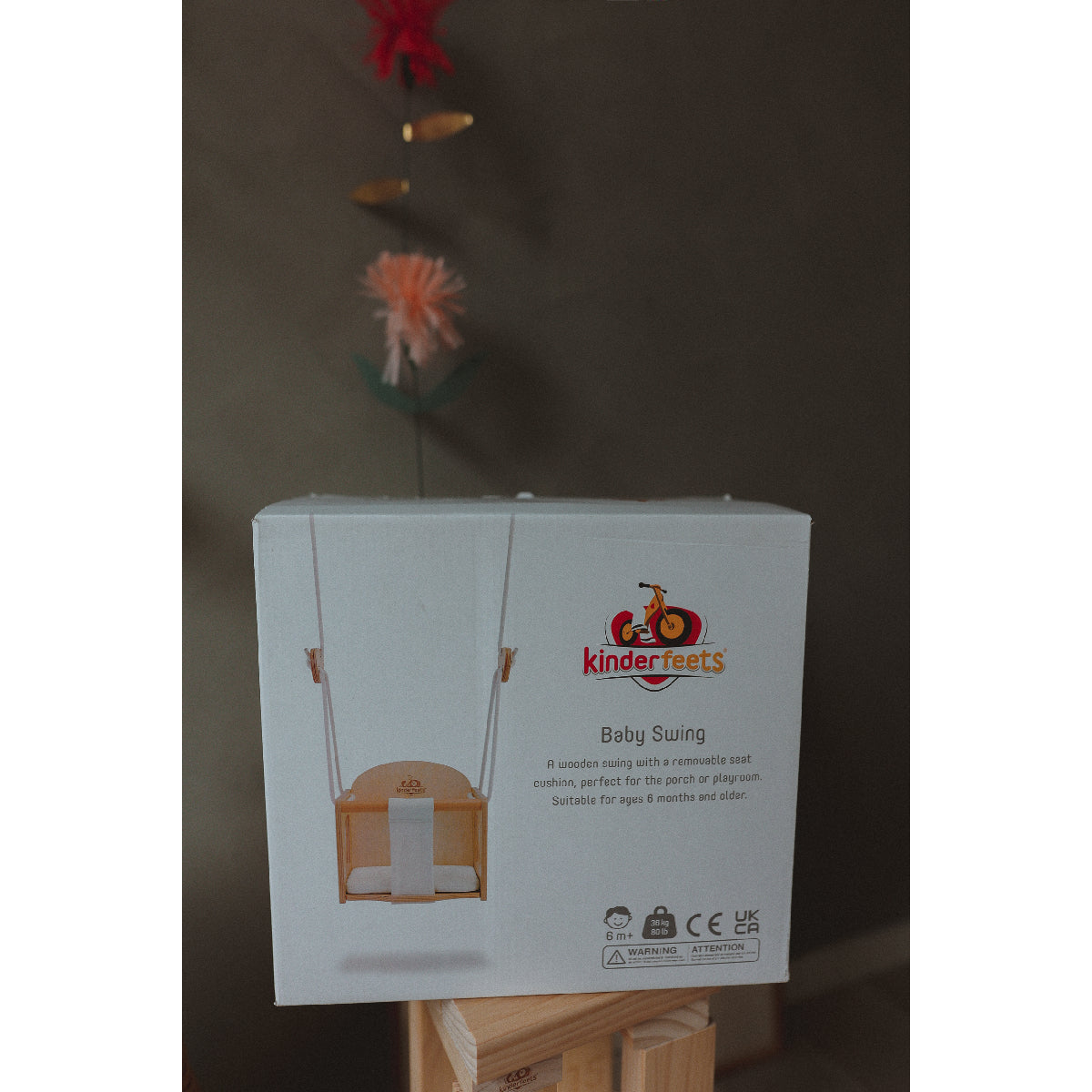 Box of Kinderfeets baby swing on a stand with a dark background