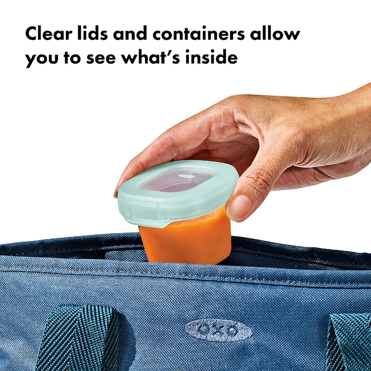 Hand holding a container with a clear lid, showing what's inside, against a blue bag background.