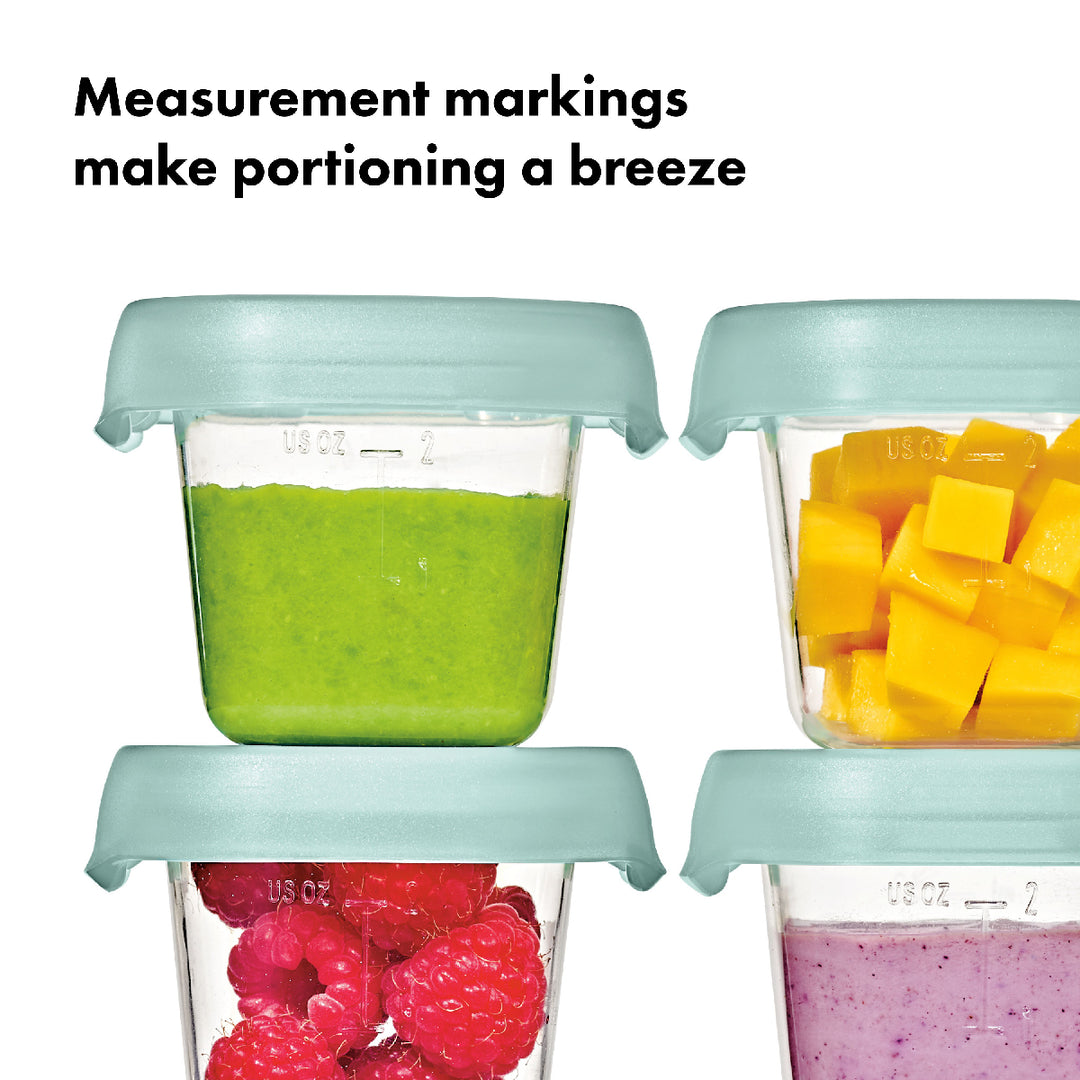 Four containers with measurement markings filled with green smoothie, yellow fruit chunks, red raspberries, and purple smoothie.