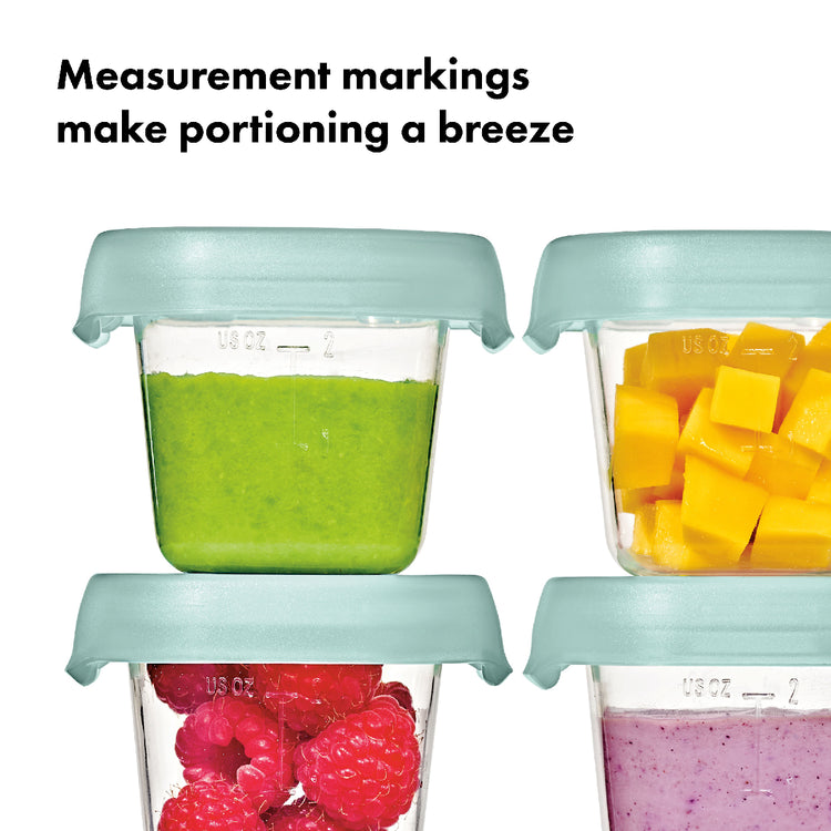 Four containers with measurement markings filled with green smoothie, yellow fruit chunks, red raspberries, and purple smoothie.