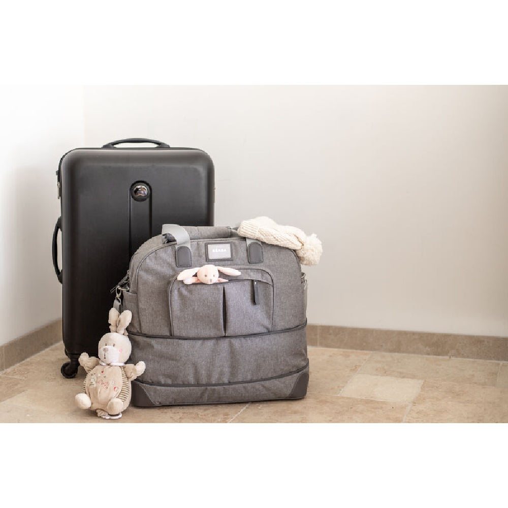 Gray backpack with teddy bear, black suitcase, and white wall background