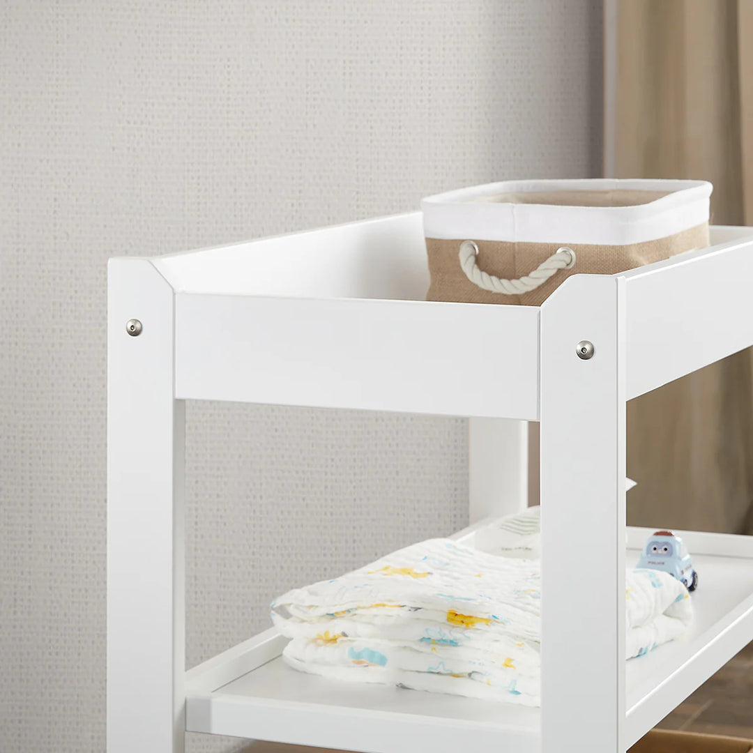 White baby changing table with a basket and blanket in a neutral setting