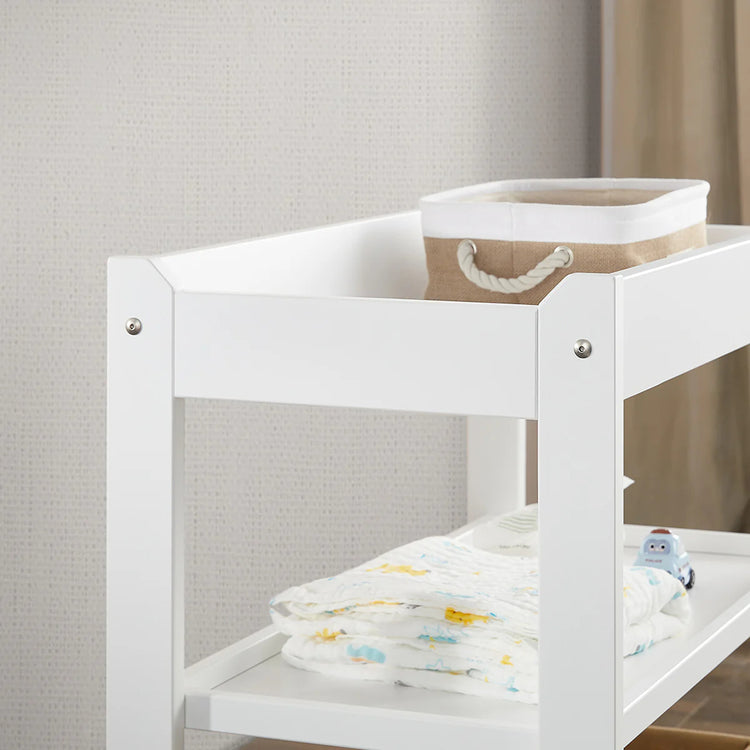 White baby changing table with a basket and blanket in a neutral setting