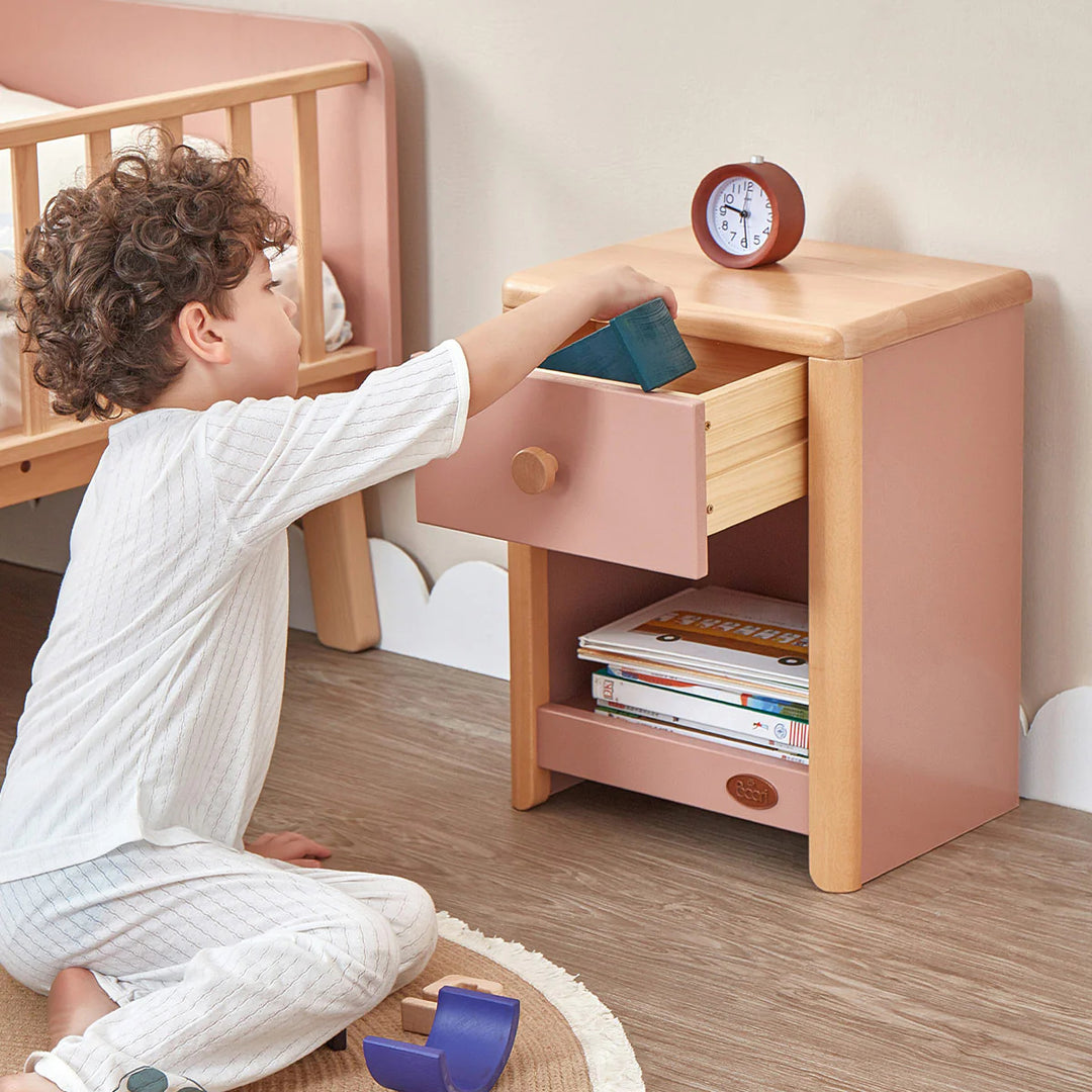 Child playing with a wooden nightstand in a child's room