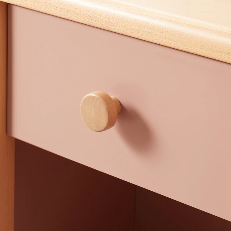 Close-up of a pink drawer with a wooden knob