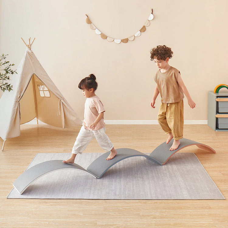 Two children playing on a wavy gray rug in a room with a teepee and toys.