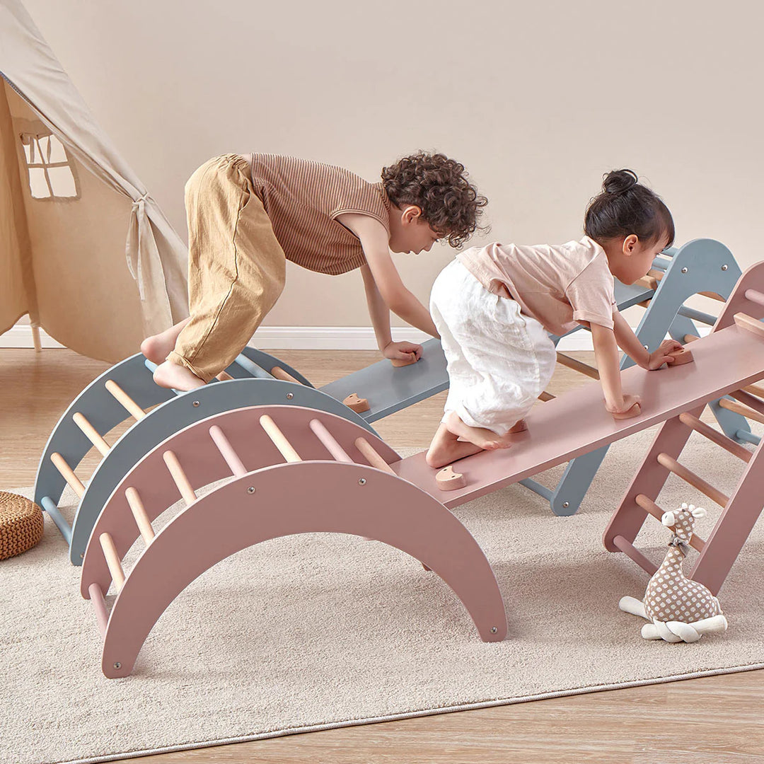 Children playing on a colorful seesaw in a room with a wooden floor and white walls.
