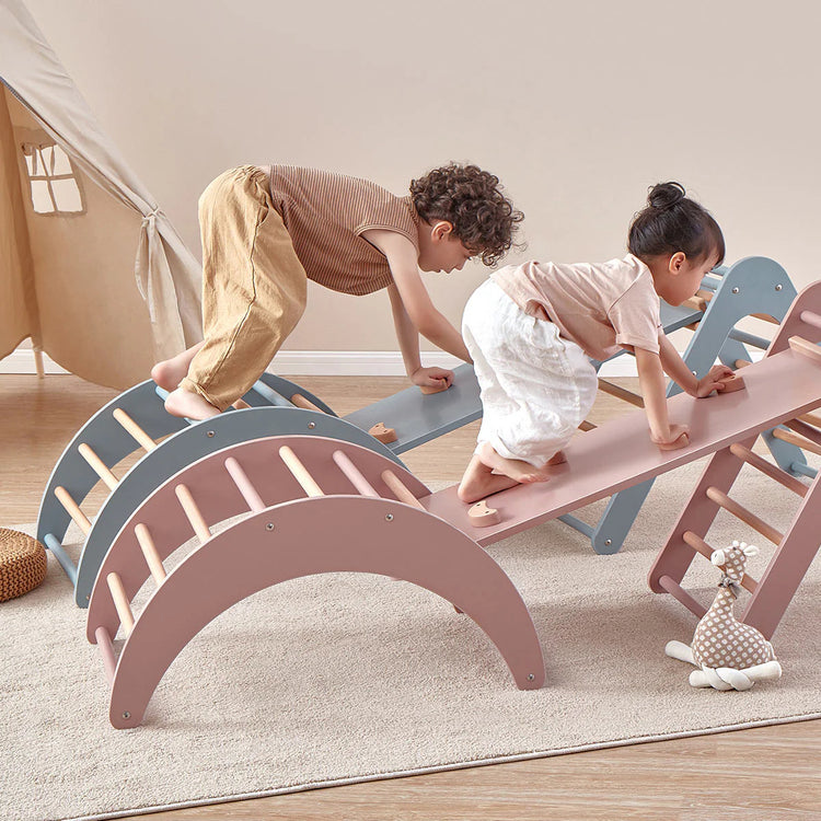 Children playing on a colorful seesaw in a room with a wooden floor and white walls.
