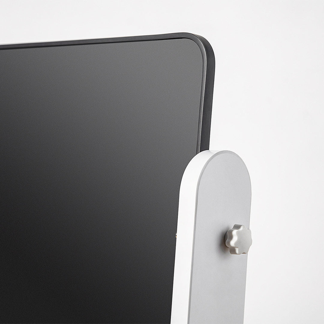 Close-up of a black electronic device with a white stand on a light gray background