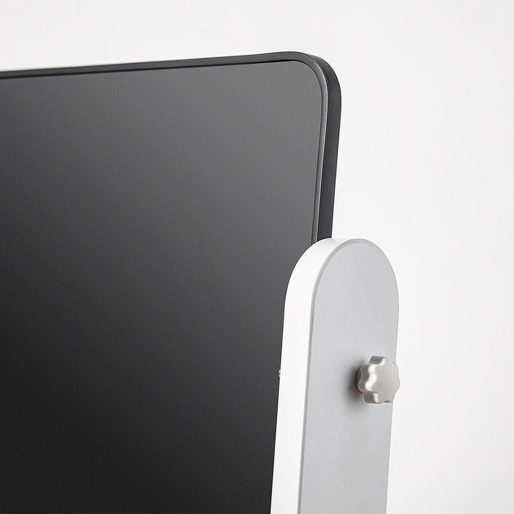 Close-up of a black electronic device with a white stand on a light gray background