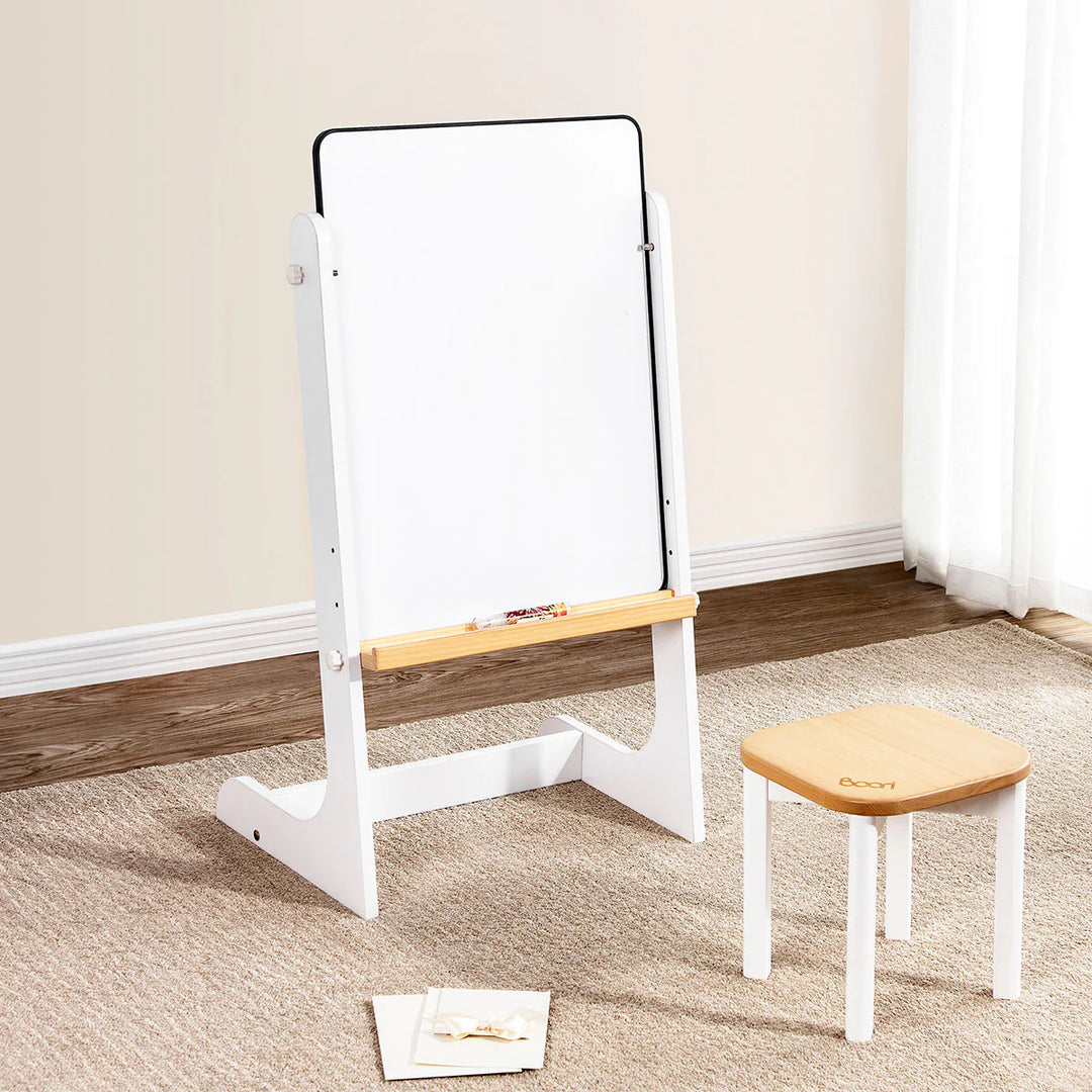 Whiteboard with wooden top and stool on a carpeted floor against a beige wall.