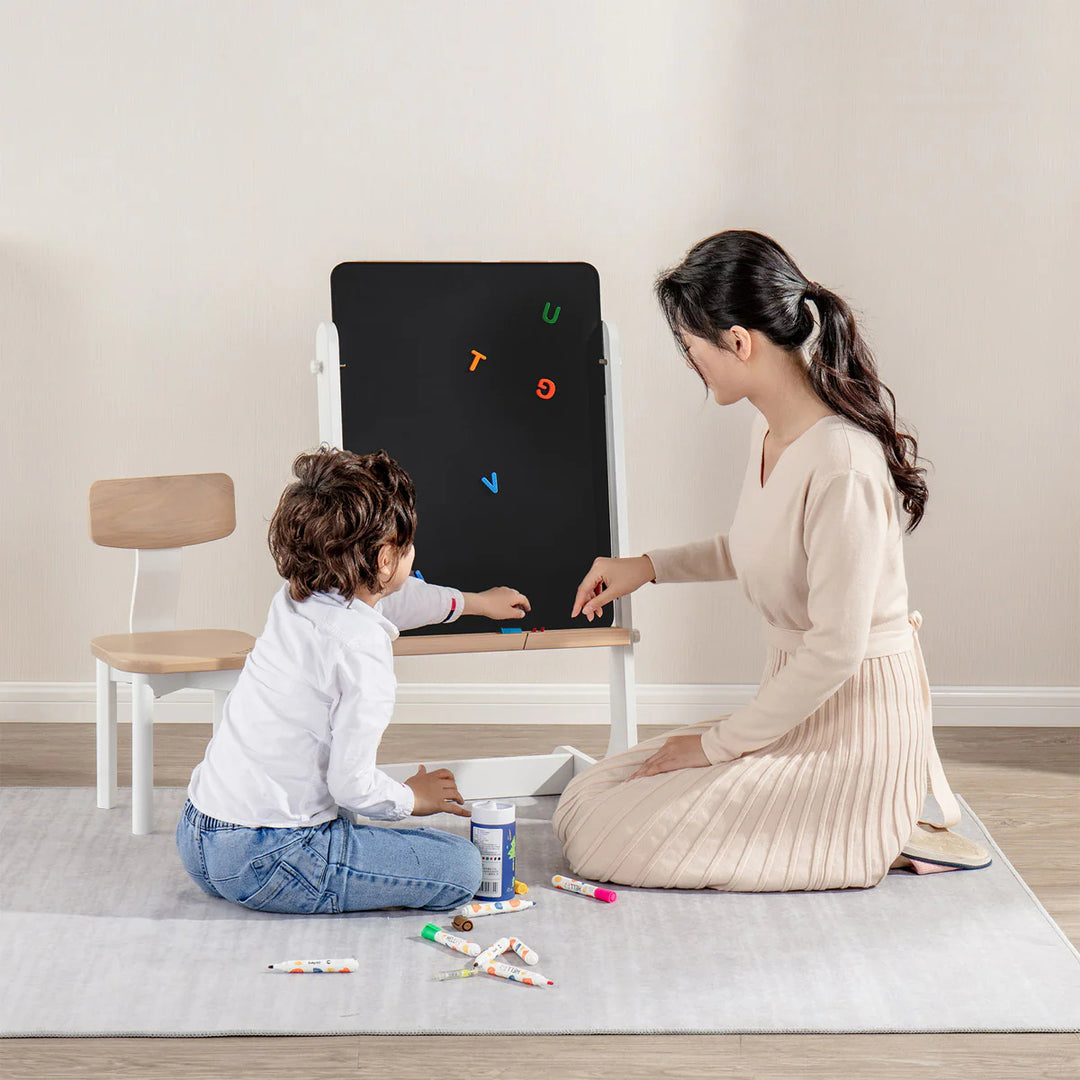 Woman and child playing with a blackboard and colorful magnets on a light-colored floor.