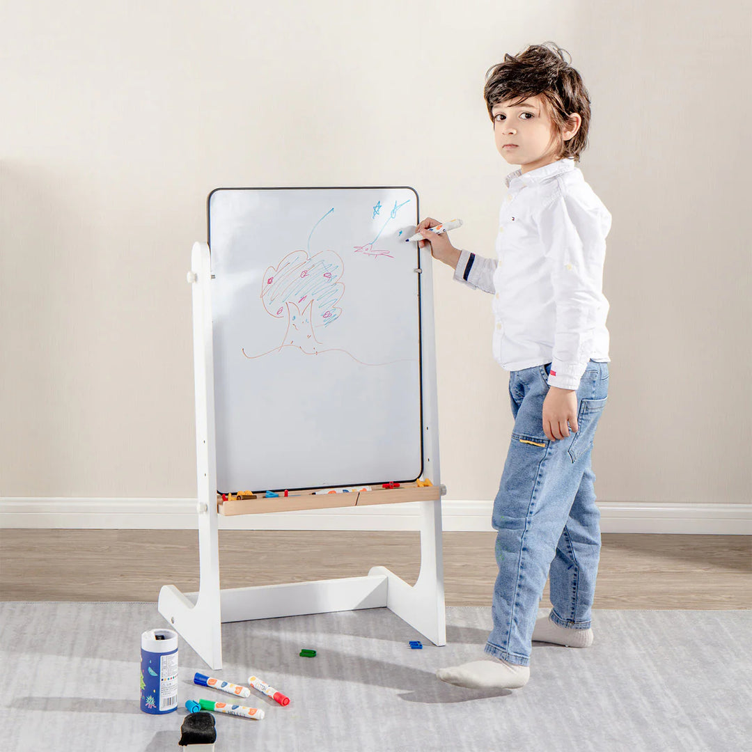 Child drawing on a whiteboard with markers in a room.