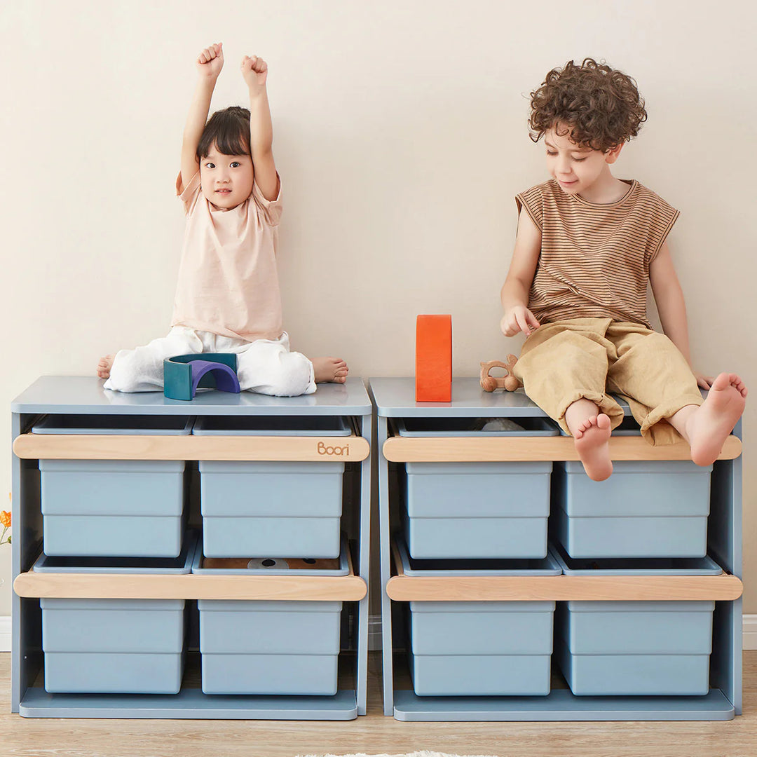 Two children playing with storage cubes on a light-colored floor.