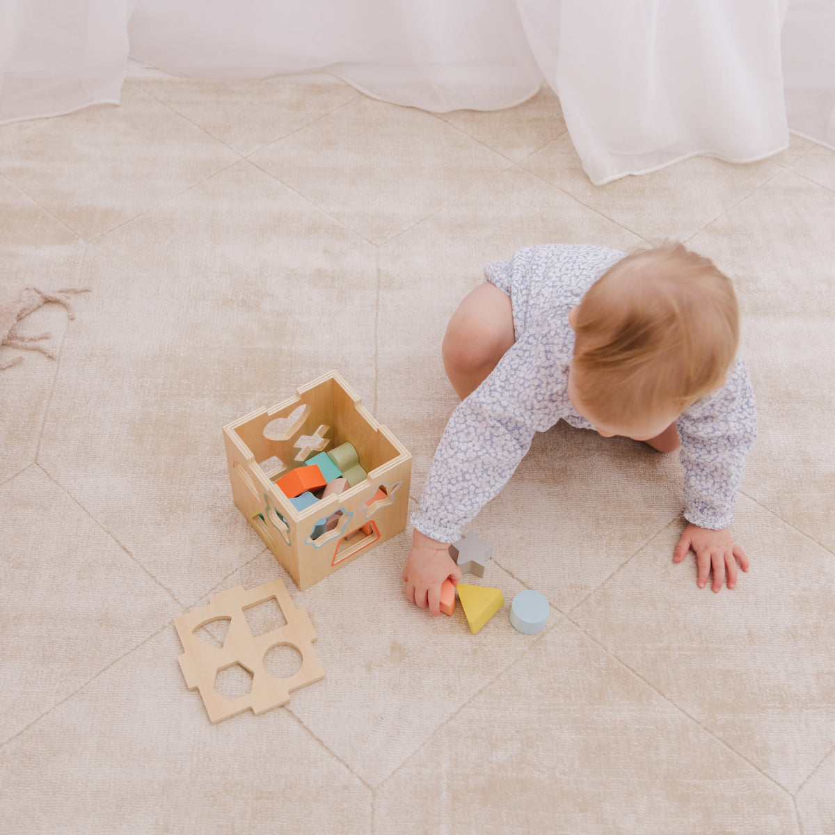 Baby playing with wooden toys on a tiled floor