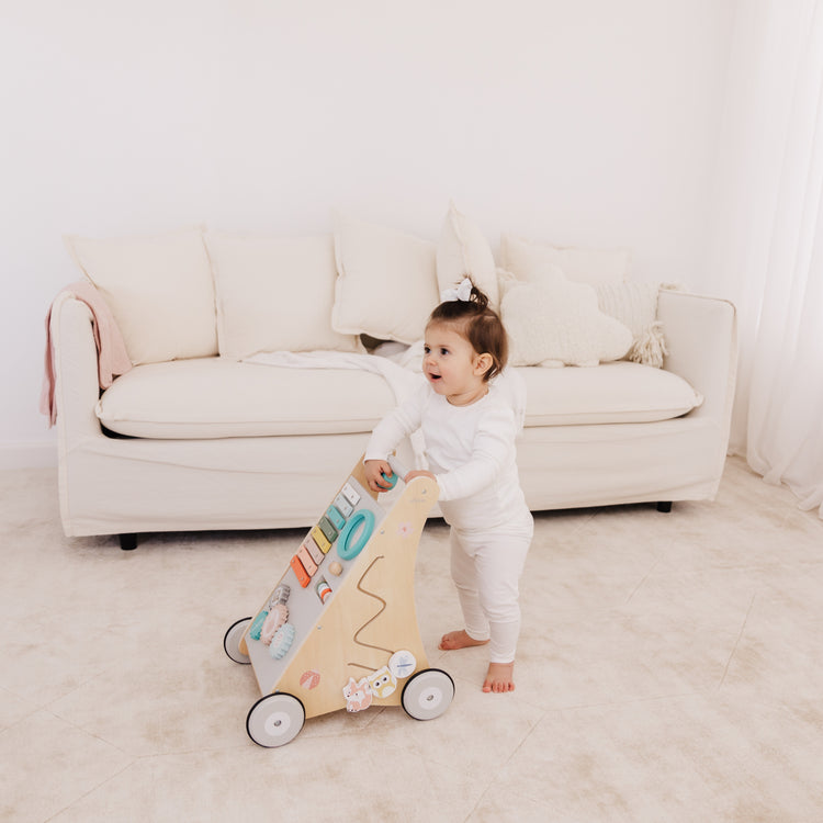 Child playing with a toy in a room with a white couch and light-colored floor.