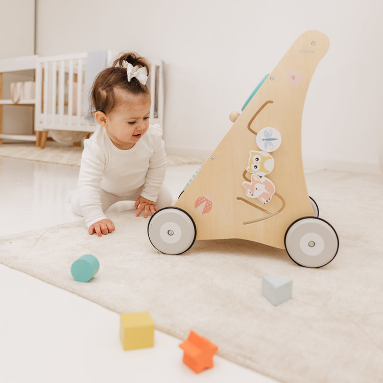 Child playing with a wooden toy car on a soft surface